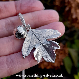 Sterling silver hawthorn leaf & berry on a silver belcher necklace held in hand