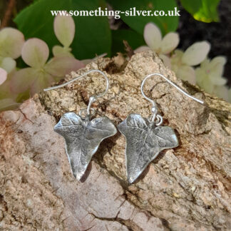 Sterling silver ivy leaf drop earrings on natural bark background