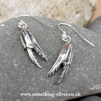 Sterling silver crab claw drop earrings on natural stone background