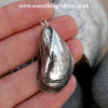 Sterling silver mussel shell pendant with belcher necklace on natural stone background held in hand