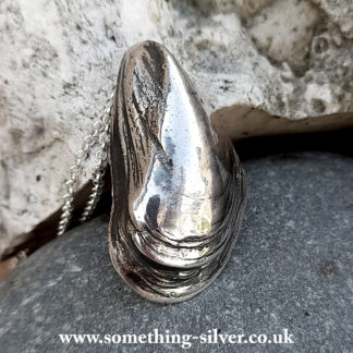 Sterling silver mussel shell pendant with belcher necklace on natural stone background