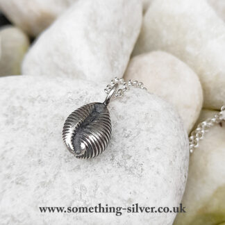 Sterling silver cowrie shell pendant with silver belcher chain on natural stone background, reverse